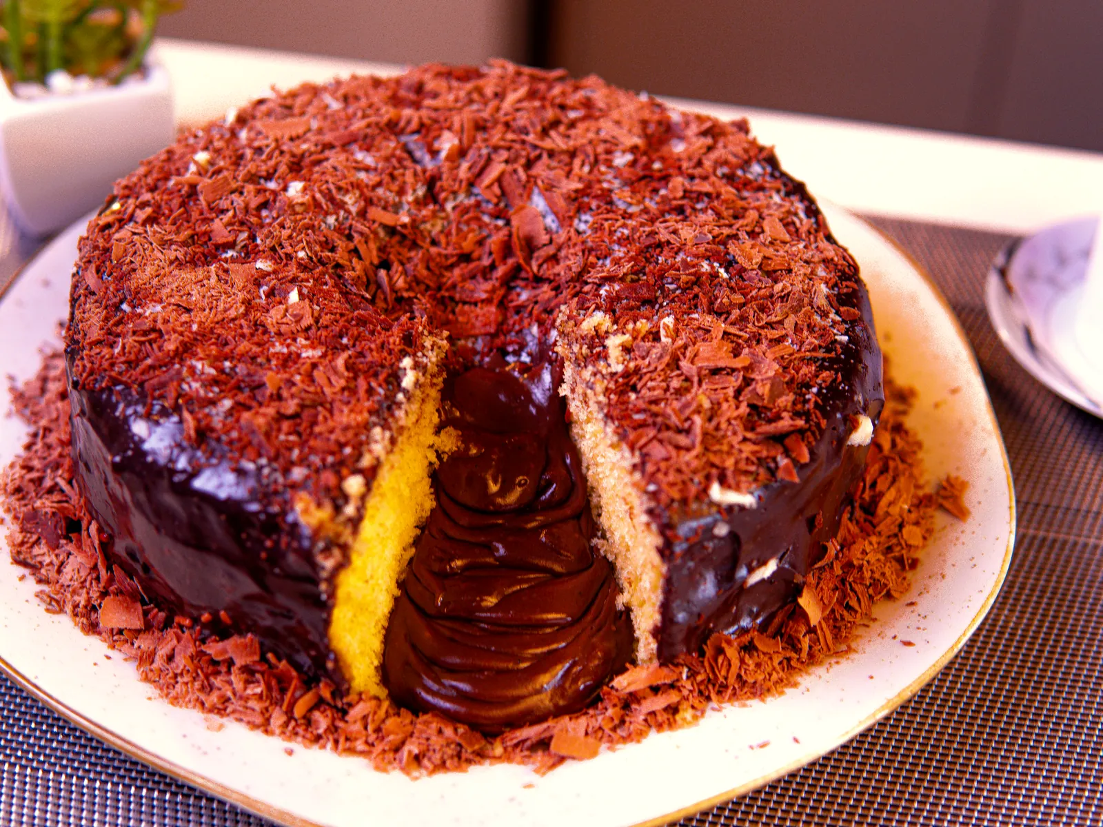 Bolo caseiro de brigadeiro cortado, com massa amarela e cobertura de chocolate